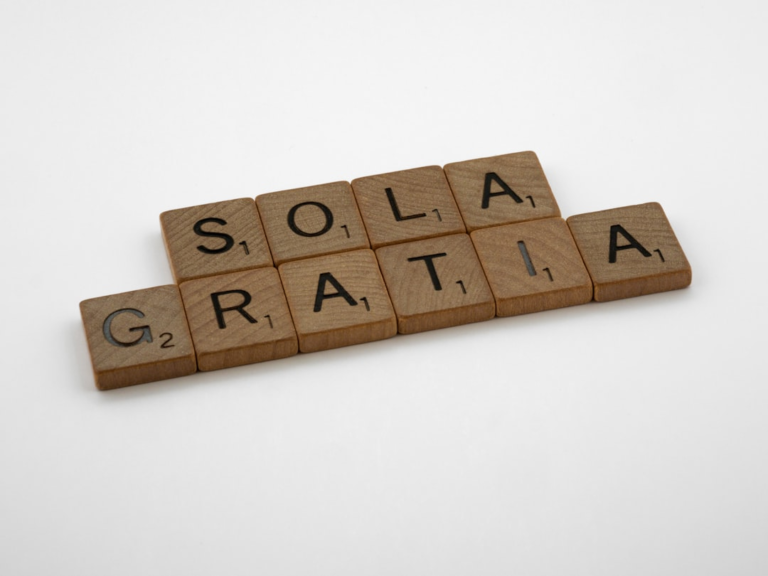 a scrabbled wooden block spelling out the word solar gratia — Foto por Brett Jordan na Unsplash